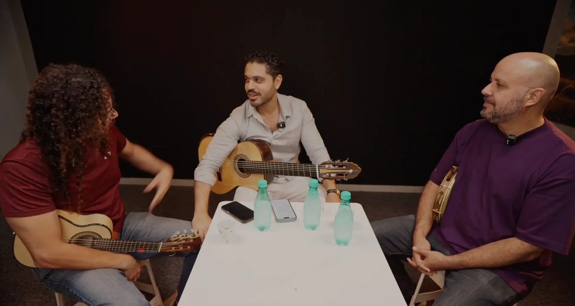 Podcast com músicos ao redor da mesa, fundo escuro