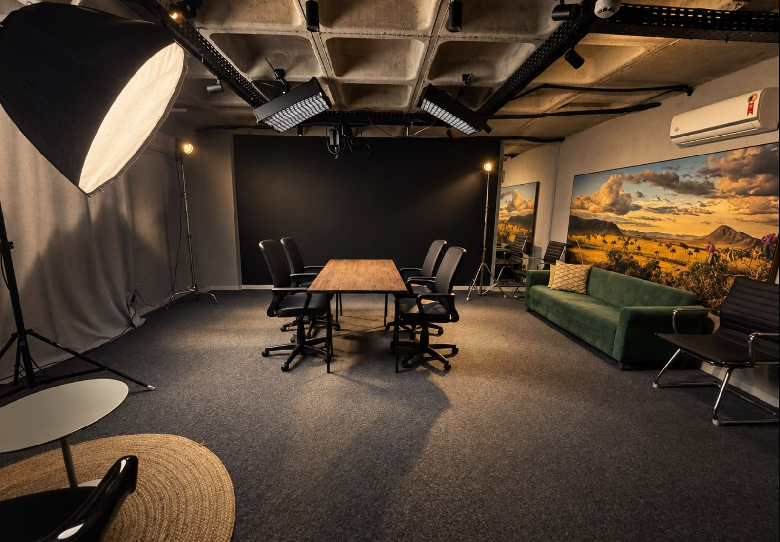 Sala principal com mesa, sofá verde e painéis de luz no teto